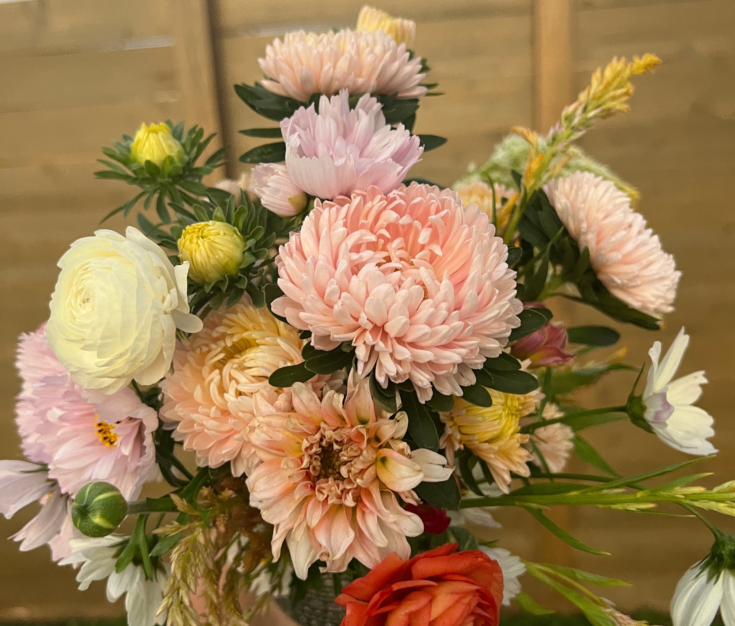 Bouquet of colorful flowers held by a person against a neutral background